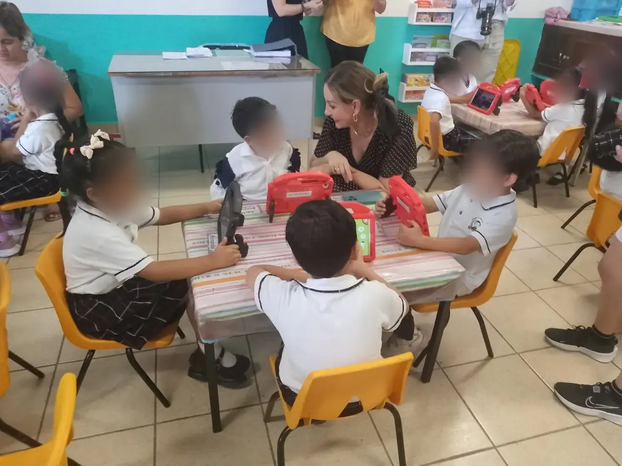 A teacher works with a group of children using tablets
